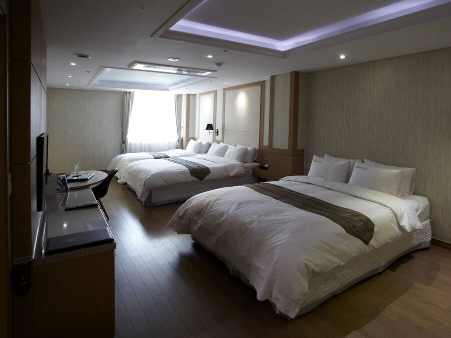 Habitación de hotel con dos camas, un escritorio y un televisor.