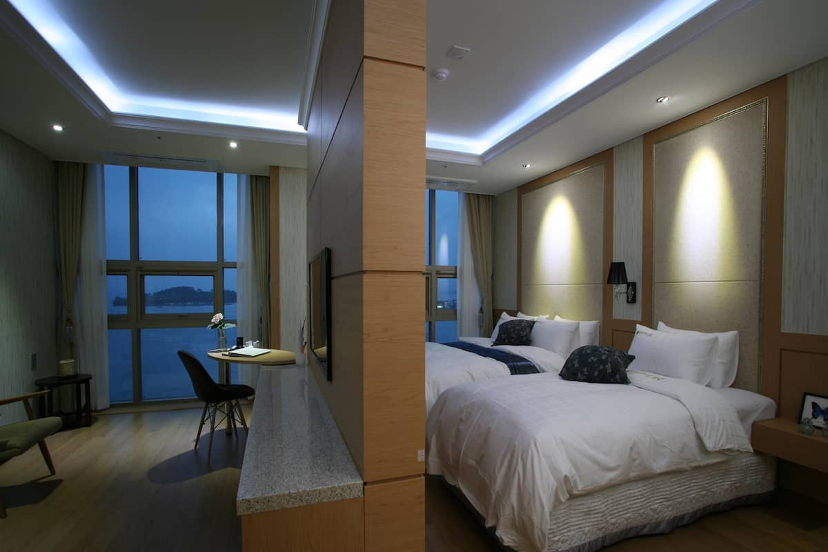 Ein Hotelzimmer mit einem großen Bett, einem Schreibtisch und Blick auf das Wasser.