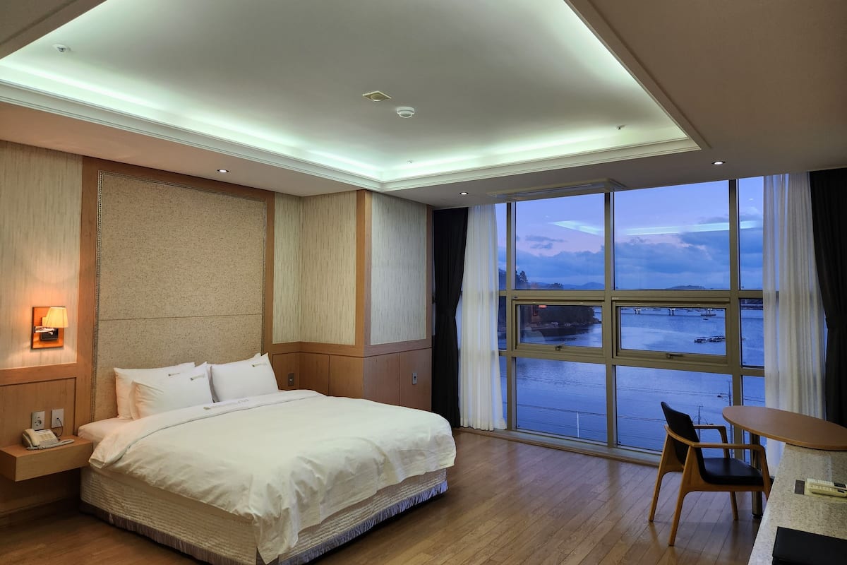 Ein Hotelzimmer mit einem großen Bett, einem Schreibtisch und Blick aufs Meer.