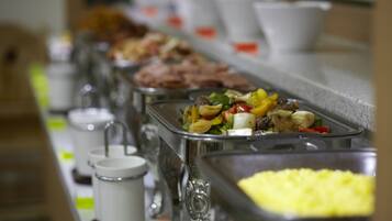 Una mesa de buffet con diversos platos, incluyendo una sección con comida amarilla y varias tazas blancas a la izquierda.