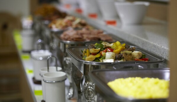 A buffet line with various dishes, including a section with yellow food, and multiple white mugs on the left. - Benikea Hotel Yeosu (Yeosu)
