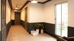 A hallway with a door at the end, a potted plant, and a basket. - Suncheon Guesthouse Nreem (Suncheon)
