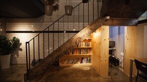 A staircase with a wooden railing leading to a lower level with a bookshelf. - Suncheon Guesthouse Nreem (Suncheon)