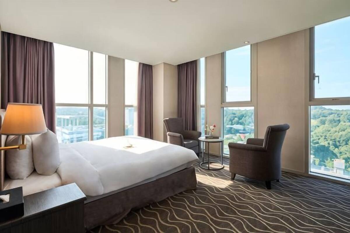 Una camera d'albergo con un letto grande, una scrivania, una sedia, un tavolino e vista sulla città.