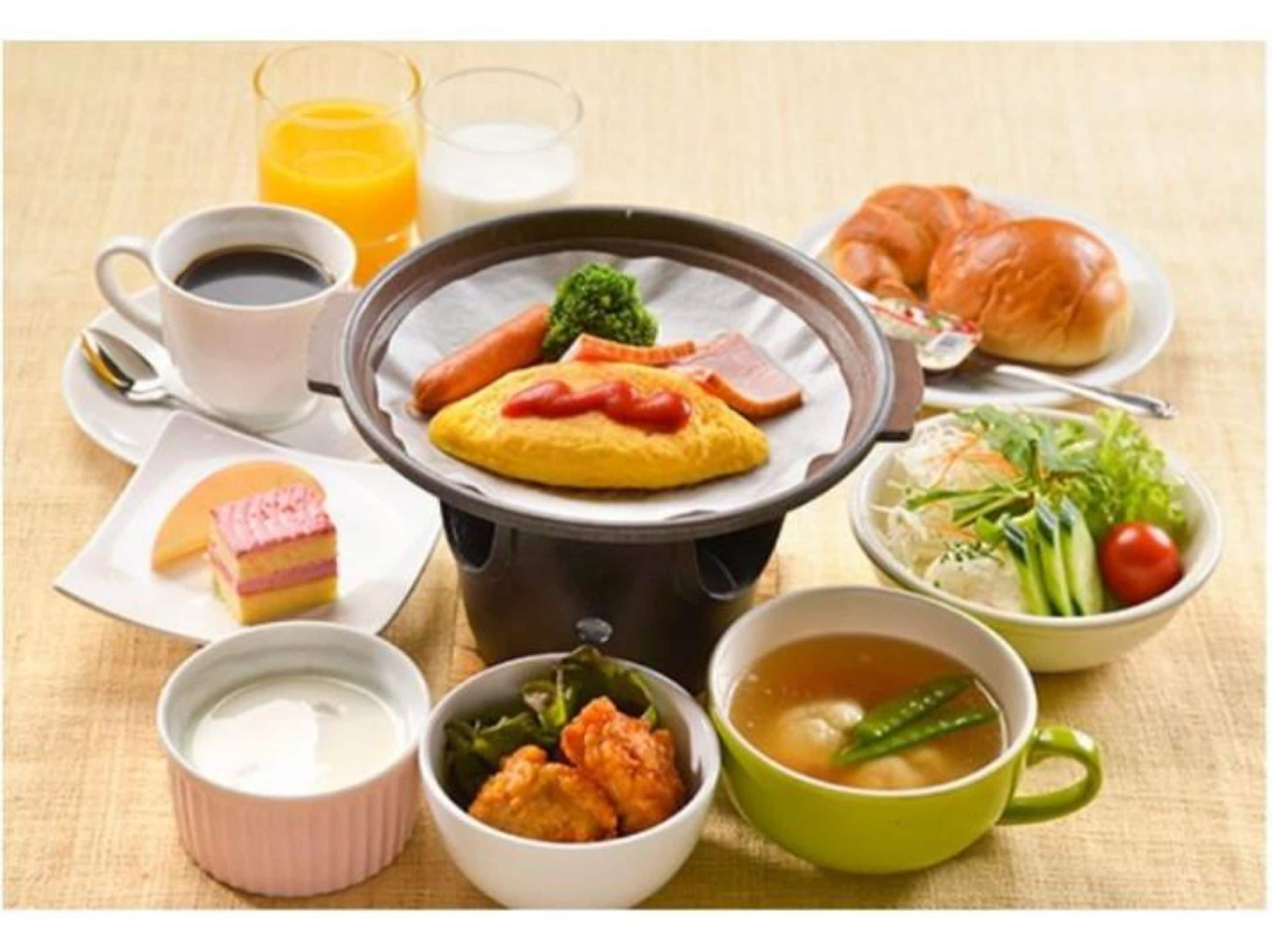 Una mesa con diversos alimentos, incluyendo un recipiente con comida caliente, un croissant, una ensalada y un postre.