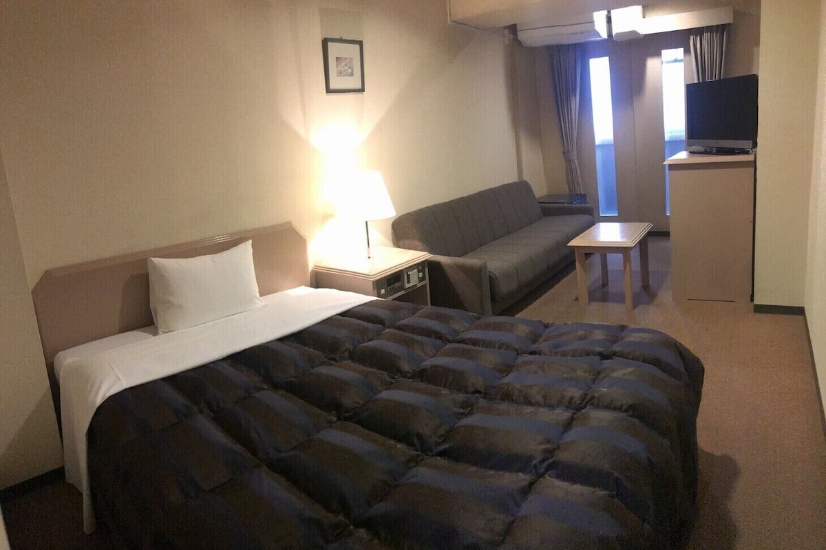 Une chambre d’hôtel avec un lit, un canapé, un bureau, une télévision et un tableau au mur.
