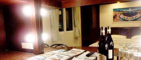 A hotel room with a wooden counter, a menu, remote controls, and a tray with glasses and bottles.