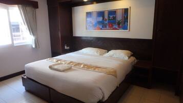 Uma cama bem arrumada em quarto de hotel, com um quadro acima, uma janela com cortinas e piso de azulejos.