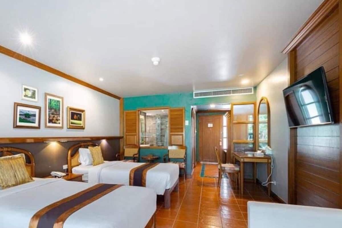 Habitación de hotel con dos camas, televisión, escritorio y baño visible a través de una puerta.