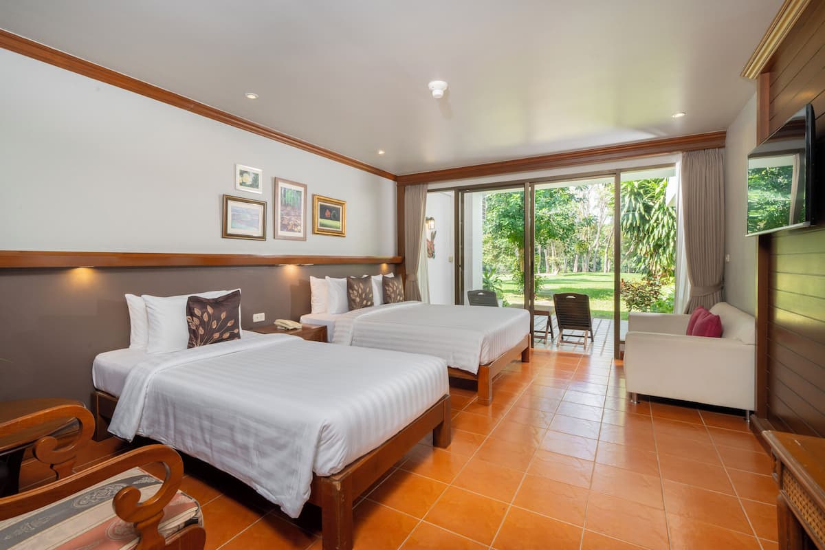 Habitación de hotel con dos camas, un sofá, un televisor y vistas al exterior.