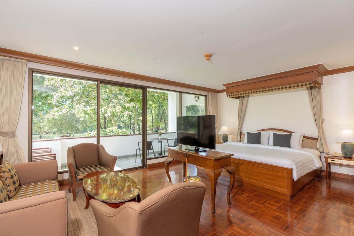 Una habitación de hotel con una cama grande, televisión, sofá y una mesa de comedor.