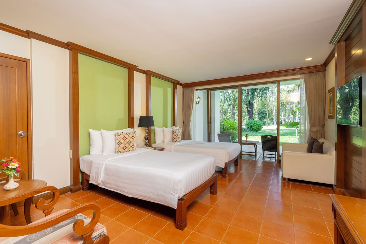 Habitación de hotel con dos camas, un sofá, un televisor y vistas al exterior.