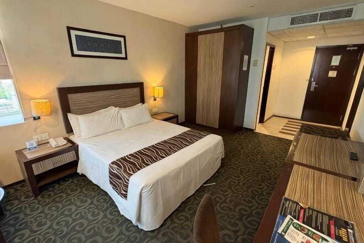 Une chambre d’hôtel avec un grand lit, des lampes de chevet, une armoire, un bureau avec une lampe et une bibliothèque.