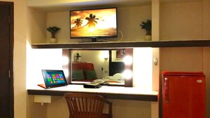 A compact hotel room with a desk, a laptop, a television, and a red refrigerator. - Paradise Inn (Karon)