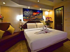 A hotel room with a bed, a painting on the wall, and a door. - Paradise Inn (Karon)