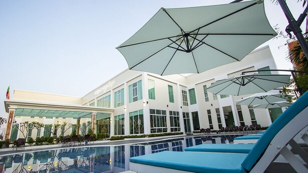 A modern hotel with a pool area, outdoor seating, and large umbrellas. - Grand Seagull Hotel (Sihanoukville)