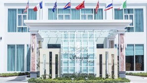 A hotel entrance with multiple flags, a glass facade, and the name "Seagull" prominently displayed. - Grand Seagull Hotel (Sihanoukville)