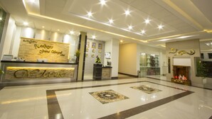 A hotel reception area with a reception desk, a wall-mounted sign, and a decorative fireplace. - Grand Seagull Hotel (Sihanoukville)