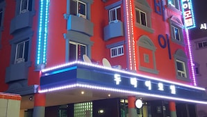 A multi-story hotel with a red facade and neon signage. - Dubai Motel (Yeosu)