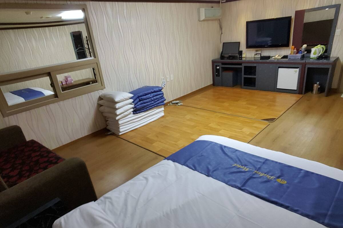 A hotel room with a bed, a desk, a television, and a mirror.