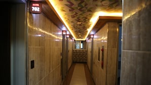 A hotel corridor with a geometric patterned ceiling, wooden walls, and a carpeted floor. - Dubai Motel (Yeosu)