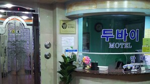A reception desk with a sign reading "Dun Tai Motel" and a potted plant beside it. - Dubai Motel (Yeosu)