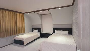 A hotel room with two beds, a curved ceiling, and a large window with curtains.