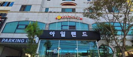 A multi-story building with a glass entrance, a parking sign, and a sign for a restaurant.
