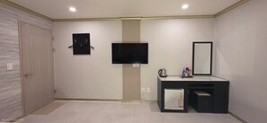 Un baño moderno con televisor de pantalla plana, un espejo y un mueble pequeño.