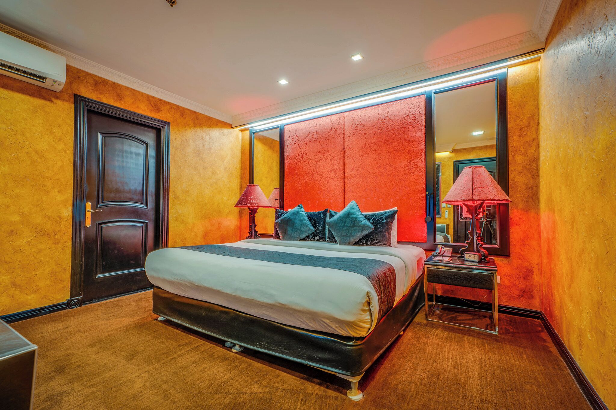 A hotel room with a large bed, two bedside lamps, a nightstand, and a mirror.