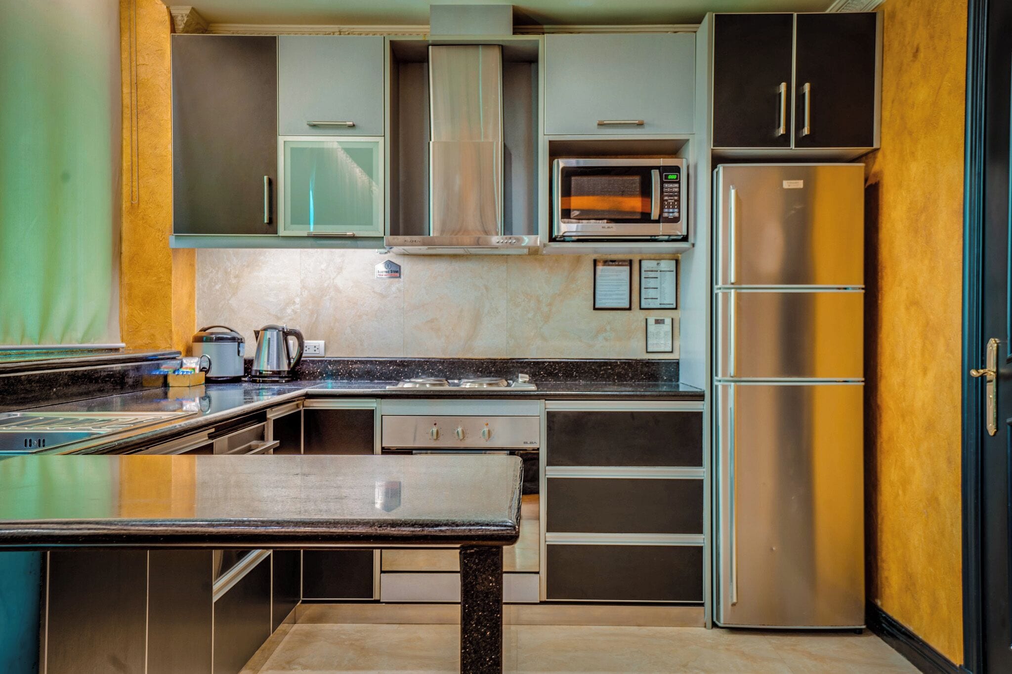 A modern kitchen with stainless steel appliances, a marble countertop, and a built-in oven.