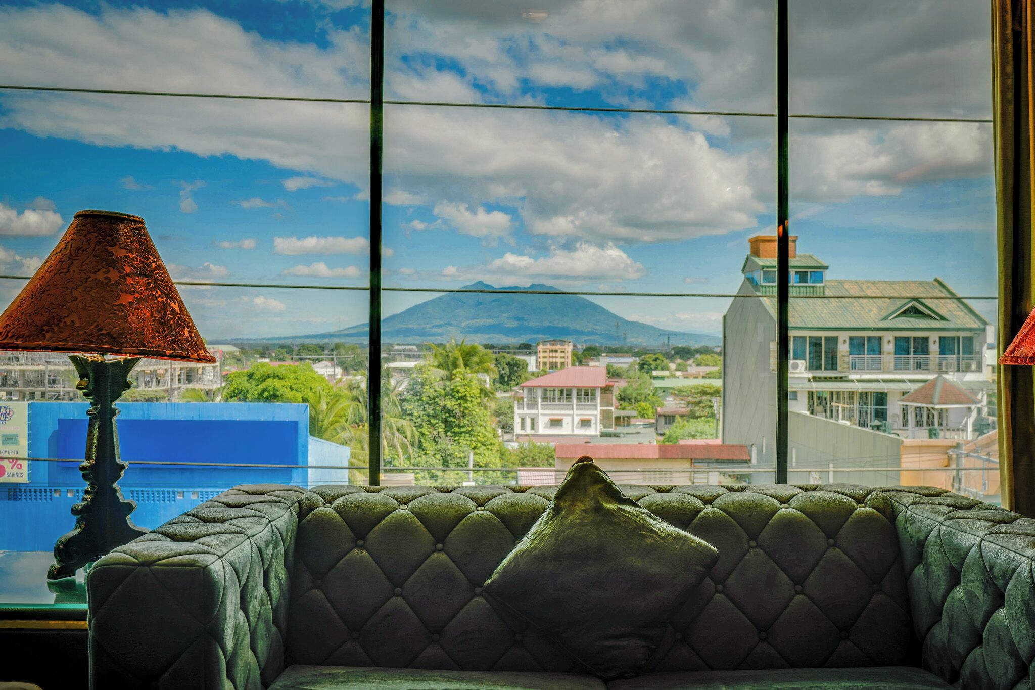 A room with a view of a mountain and buildings.