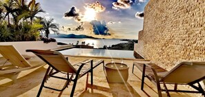 A poolside area with lounge chairs and a table, overlooking a body of water and mountains. - 3 Bedroom Sea View Villa Escape SDV086-By Samui Dream Villas  (Koh Samui)