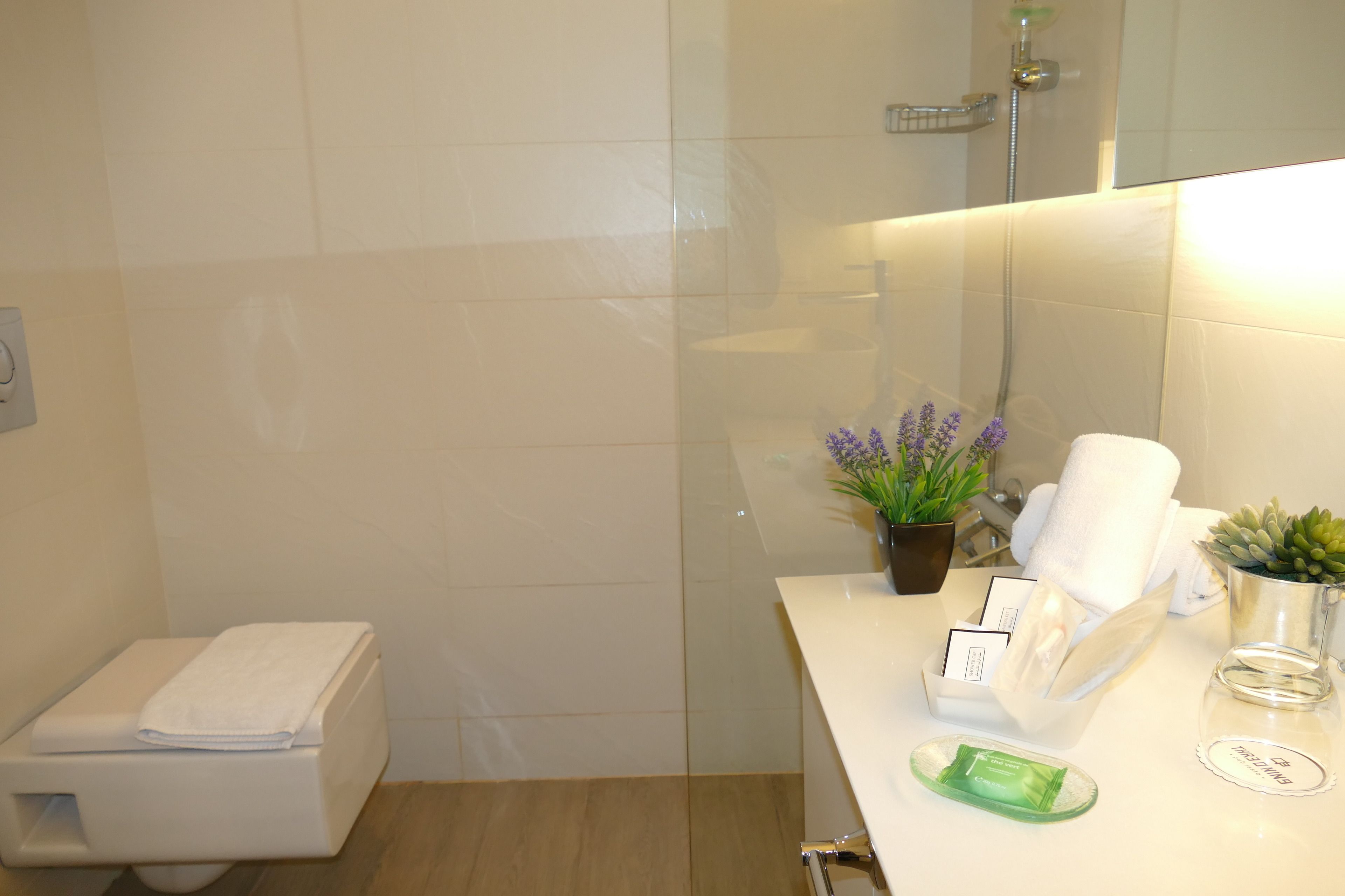 Un baño con inodoro, lavabo con artículos de aseo y zona de ducha.