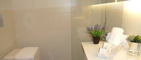Un baño con inodoro, lavabo con artículos de aseo y zona de ducha.