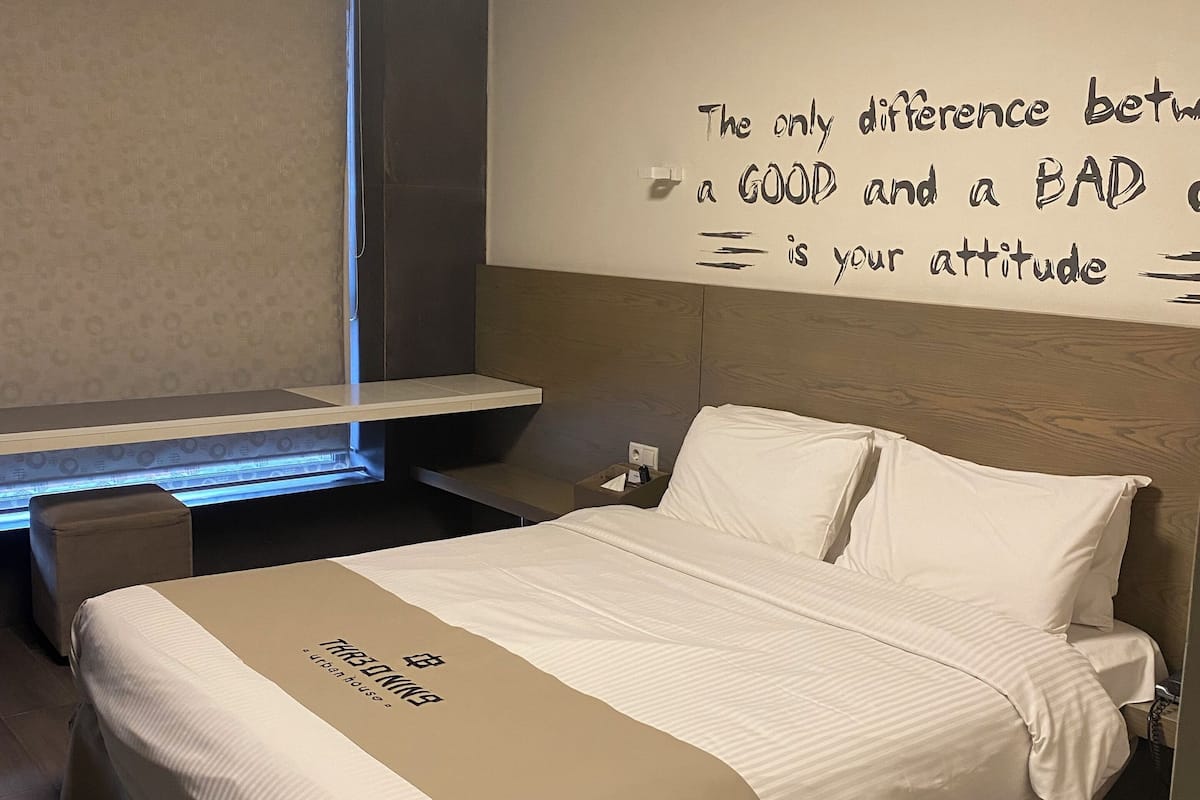 Habitación de hotel con cama, escritorio y una cita motivacional en la pared.