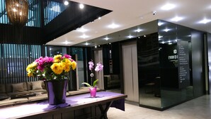 A modern hotel lobby with a reception desk, a sofa, and a large window. - Three ONine Urban House (Beirut)