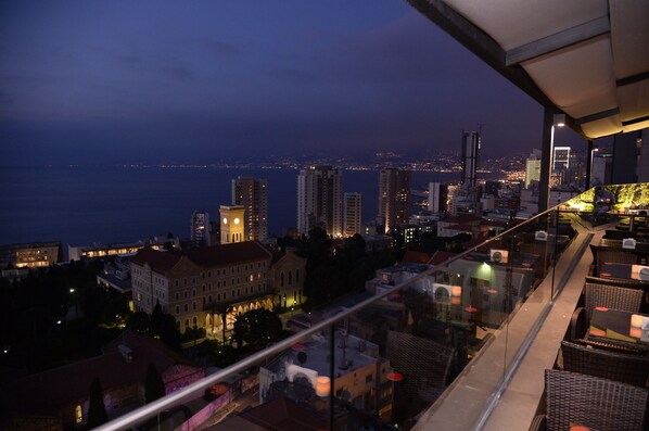 Paisagem urbana ao entardecer com vista para a orla marítima e edifícios altos.