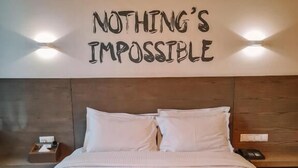 A neatly made bed with a white comforter and two pillows, a wooden headboard, and a motivational quote on the wall above the bed. - Three ONine Urban House (Beirut)