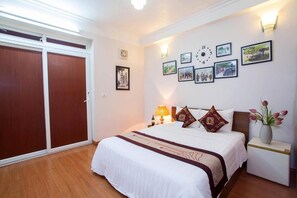 A bedroom with a large bed, a nightstand, a wall clock, and framed pictures. - Bluebell Hotel (Hanoi)