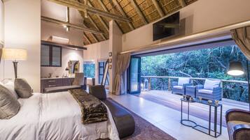 A bedroom with a large bed, a desk, and a balcony with outdoor seating.
