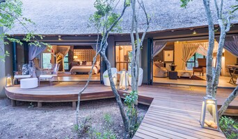 Uma área de estar externa moderna com um deck de madeira, assentos e uma estrutura de telhado de palha.