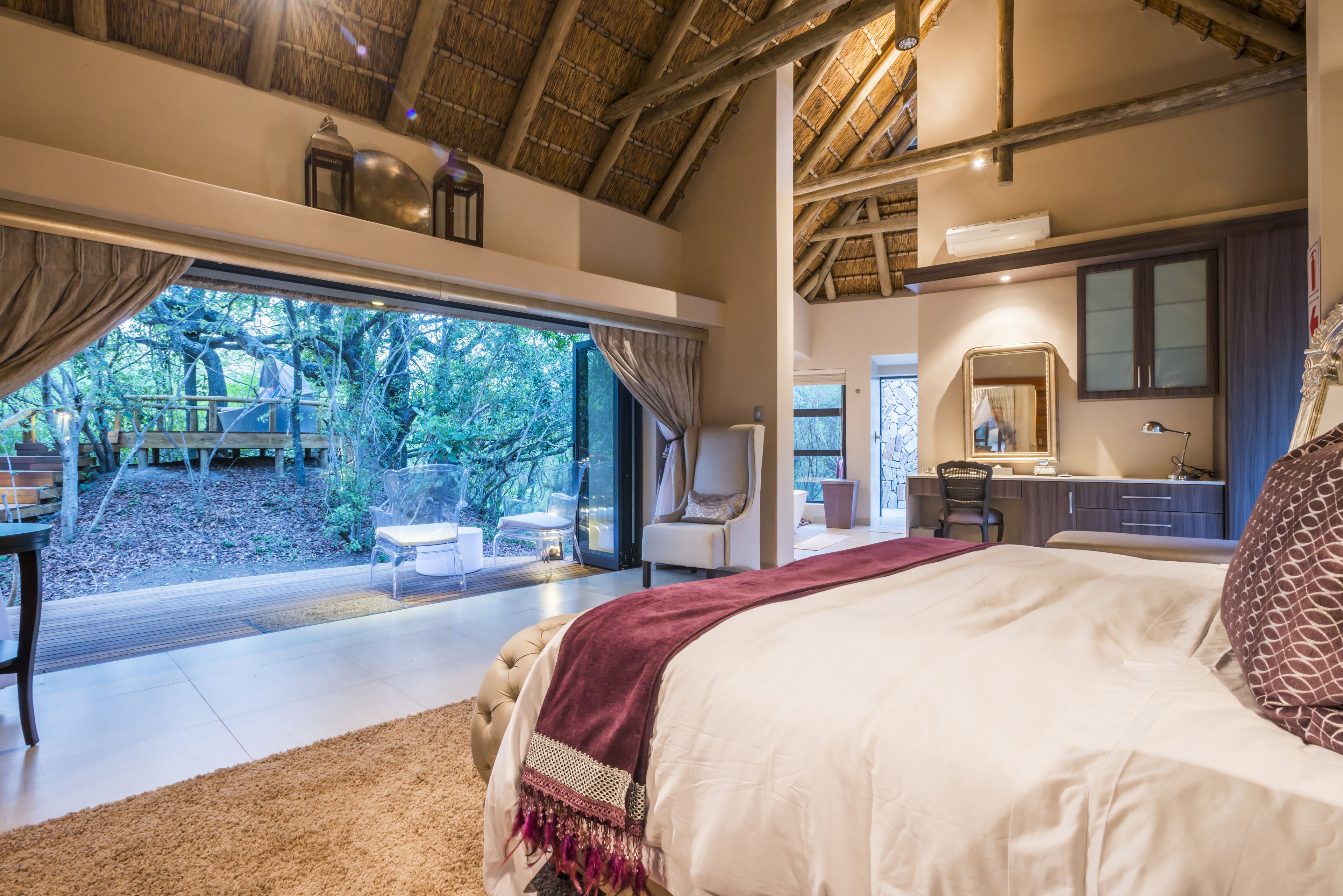 Un dormitorio con una cama grande, un escritorio, una silla y vistas al exterior.