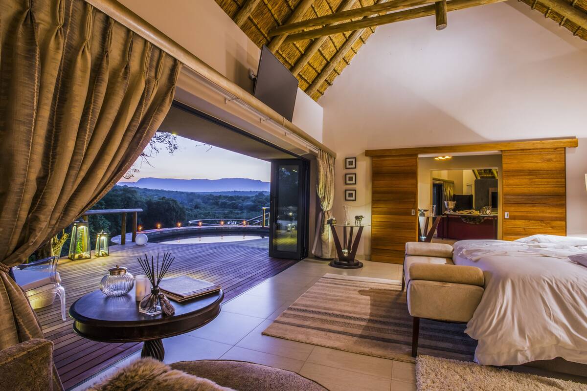 A modern bedroom with a large window, a wooden ceiling, and a view of the outdoors.