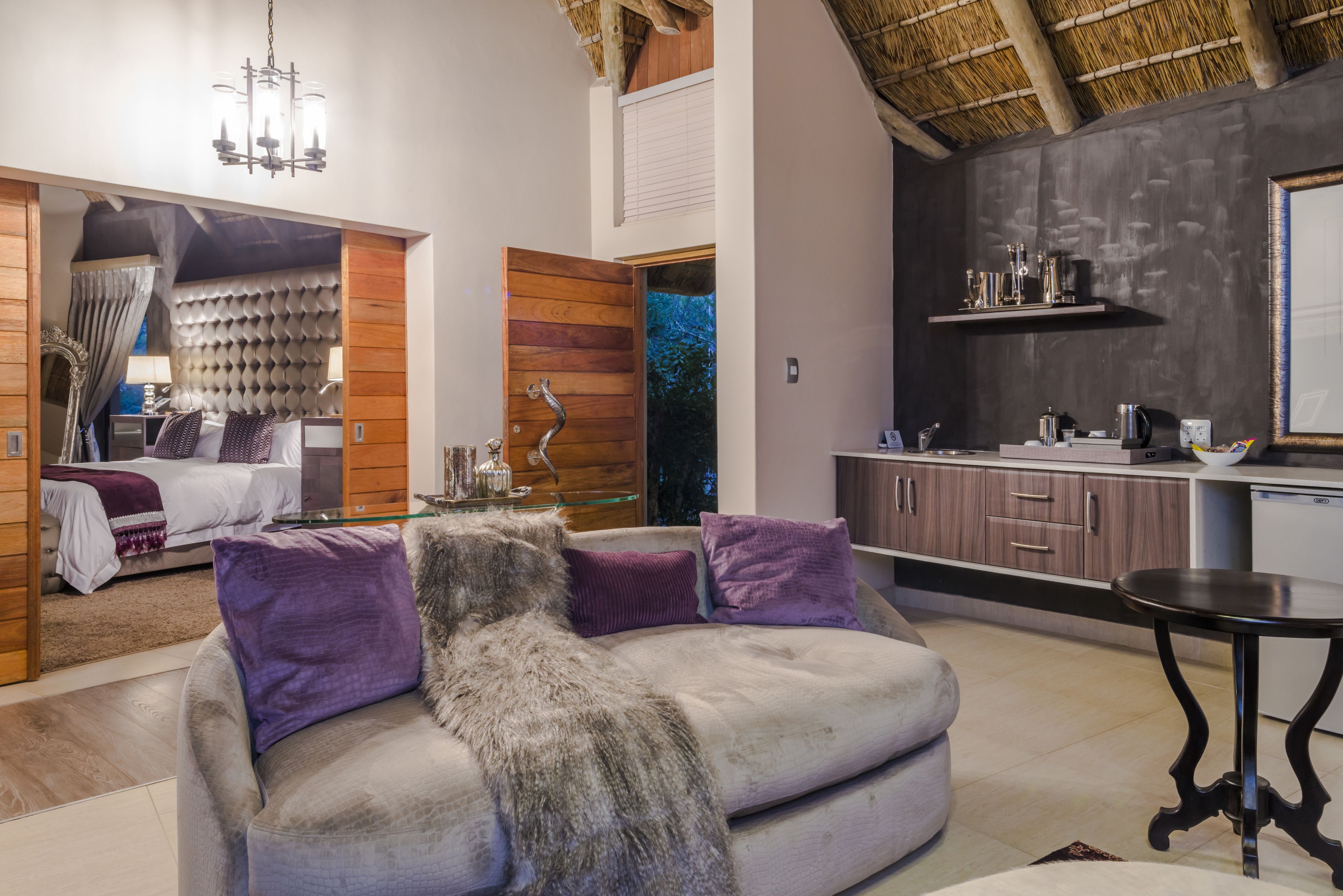 A modern living room with a sofa, a dining table, and a kitchen area.