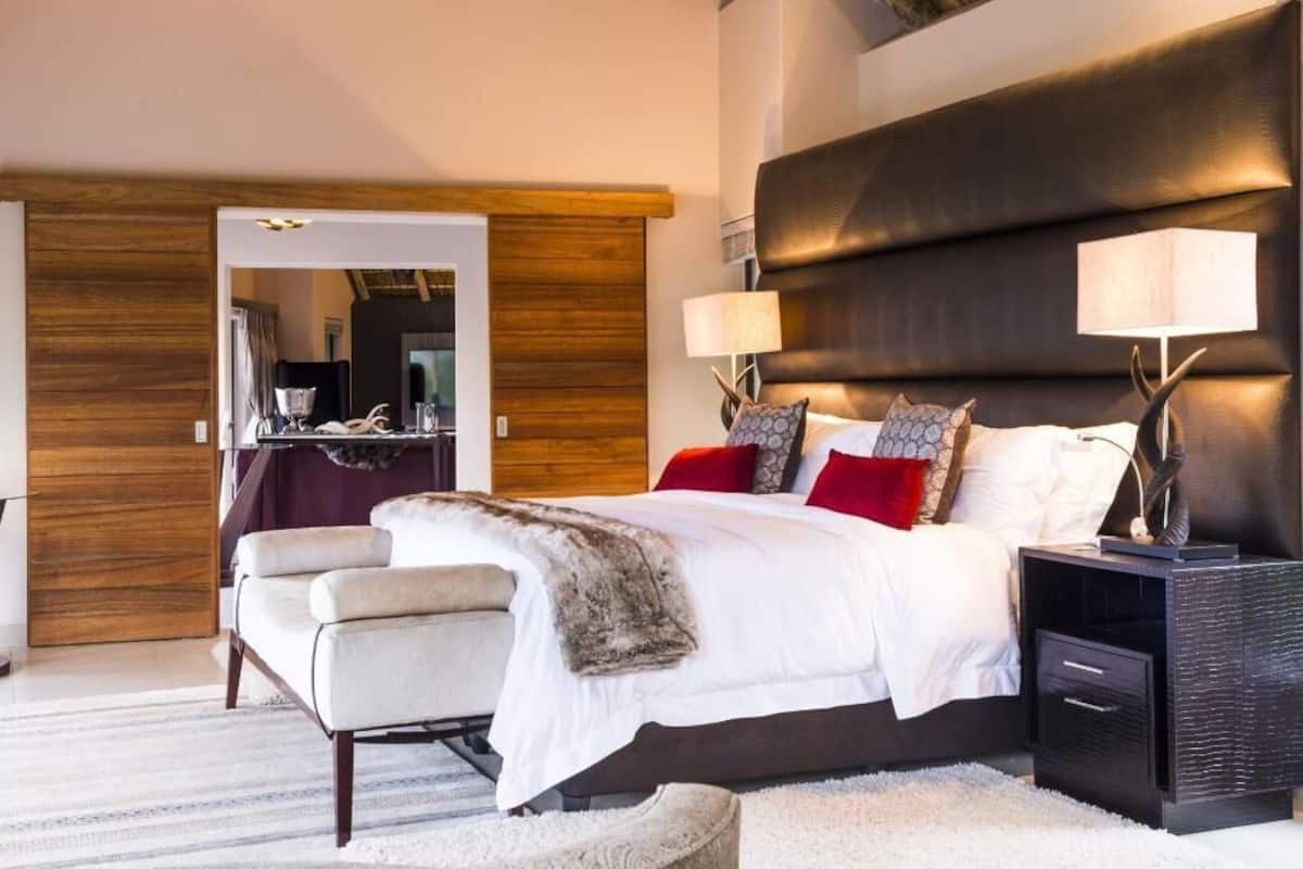 A bedroom with a large bed, bedside tables, a chair, and a wooden wardrobe.