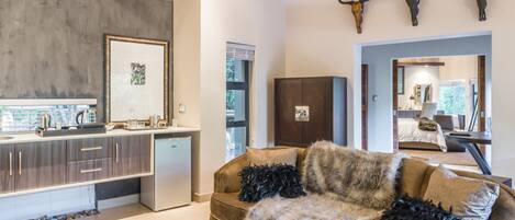 Una sala de estar moderna con un sofá, una mesa de centro de vidrio y una cocina con un lavamanos y armarios.