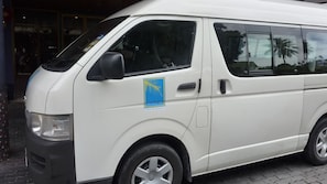 En vit skåpbil stod parkerad utanför en byggnad med en blå och gul logotyp på sidan.