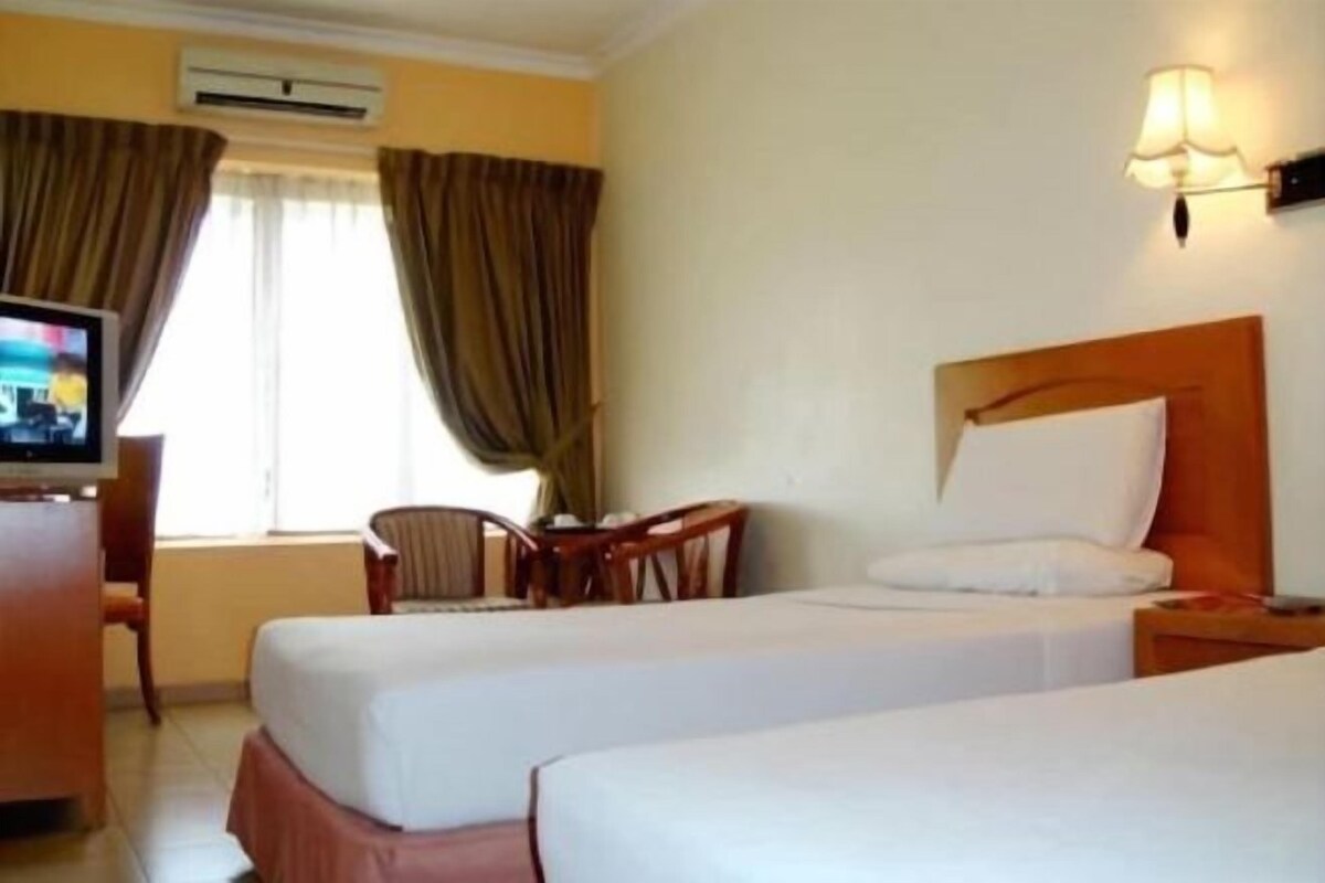 Une chambre d’hôtel avec deux lits, une télévision, un bureau et une chaise.