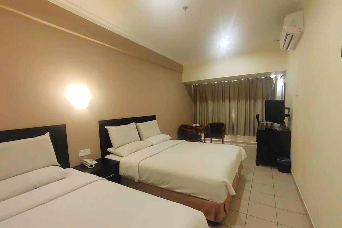 A hotel room with two beds, a desk with a chair, a TV, and a telephone.